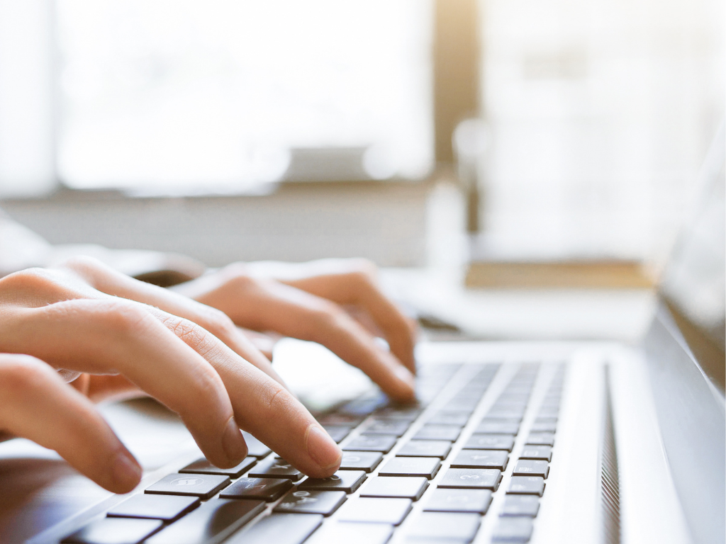 Hands typing on laptop keyboard