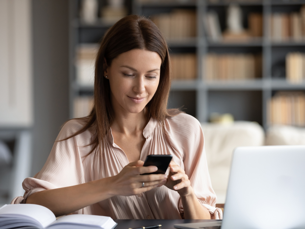 woman holding mobile device at desk